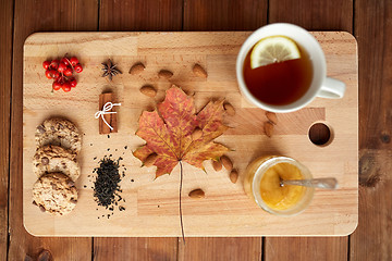 Image showing cup of tea with lemon, honey and cookies on board