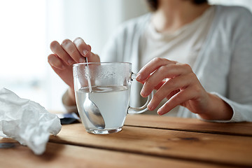 Image showing woman stirring medication in cup with spoon