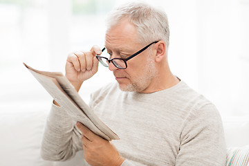 Image showing senior man in glasses reading newspaper at home