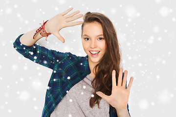 Image showing smiling teenage girl showing hands over snow