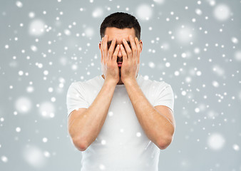 Image showing man covering his face with hands over snow