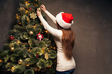 Image showing Happy woman decorating a christmas tree