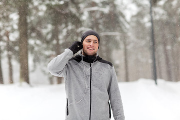 Image showing happy sports man with earphones in winter forest