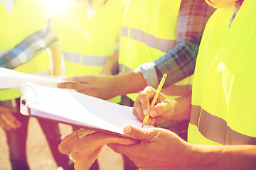 Image showing close up of builders in vests writing to clipboard