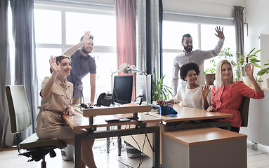 Image showing happy creative team waving hands in office