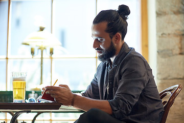 Image showing close up of man with beer and notebook at pub