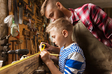 Image showing father and son with ruler measure wood at workshop