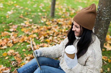 Image showing woman with tablet pc and coffee in autumn park