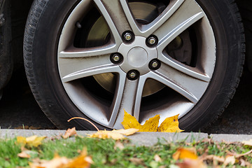 Image showing close up of car wheel and autumn leaves