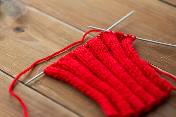 Image showing hand-knitted item with knitting needles on wood