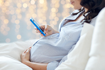 Image showing close up of pregnant woman with smartphone in bed