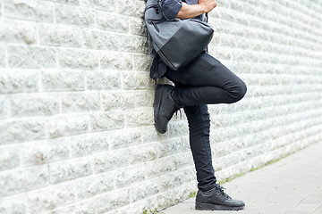 Image showing close up of man with backpack standing at wall