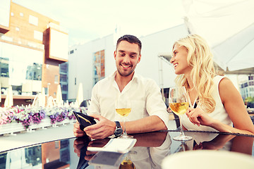 Image showing happy couple with wallet paying bill at restaurant