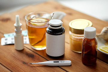 Image showing drugs, thermometer, honey and cup of tea on wood