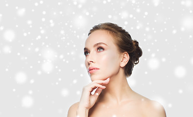 Image showing beautiful young woman touching her face over snow