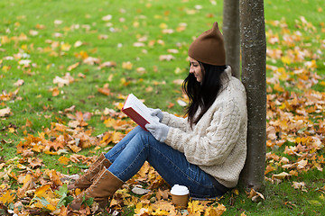 Image showing woman with book drinking coffee in autumn park