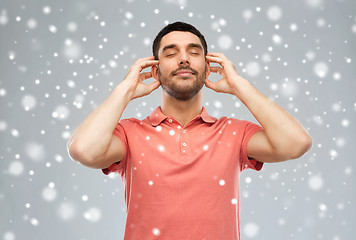 Image showing happy man listening to music over snow background