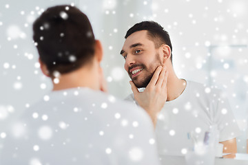 Image showing happy young man looking to mirror at home bathroom