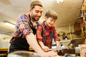 Image showing boy and dad with calipers measure wood at workshop