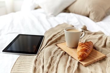 Image showing tablet pc, coffee and croissant on bed at home