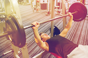 Image showing young man flexing muscles with barbell in gym