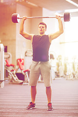 Image showing young man flexing muscles with barbell in gym