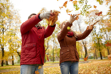 Image showing happy young couple throwing autumn leaves in park