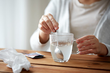 Image showing woman stirring medication in cup with spoon