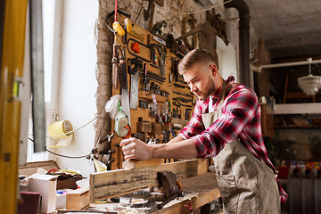 Image showing carpenter working with plane and wood at workshop