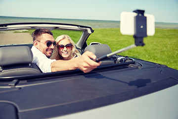 Image showing happy couple in car taking selfie with smartphone