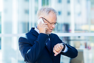 Image showing senior businessman calling on smartphone in city