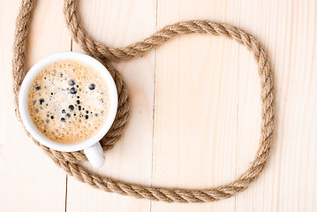 Image showing Cup of coffee with foam on wooden table