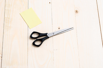 Image showing A man is cutting a sheet of yellow paper using metallic scissors