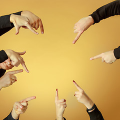 Image showing Many hands pointing ahead or out on orange background