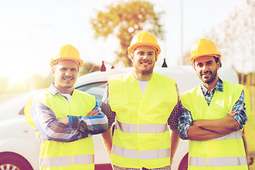 Image showing group of smiling builders in hardhats outdoors