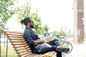 Image showing man with backpack sitting on city street bench