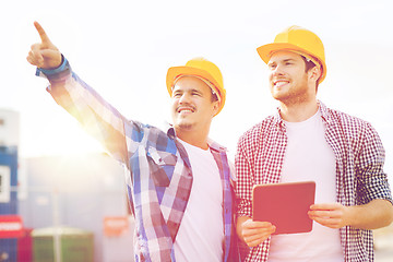 Image showing smiling builders in hardhats with tablet pc