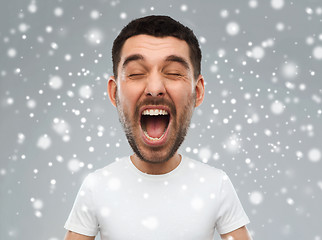 Image showing crazy shouting man in t-shirt over snow background