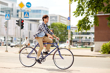 Image showing young hipster man with bag riding fixed gear bike