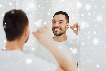 Image showing man cleaning ear with cotton swab at bathroom