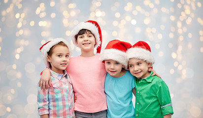 Image showing happy little children in santa hats hugging
