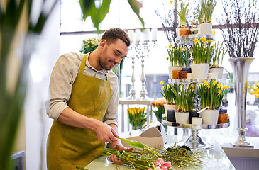 Image showing smiling florist man making bunch at flower shop