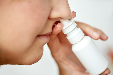 Image showing close up of sick woman using nasal spray