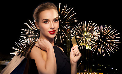 Image showing woman with bank card and shopping bags on firework