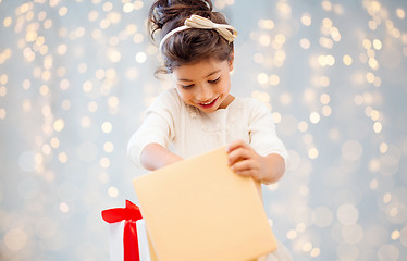 Image showing smiling little girl opening gift box over lights