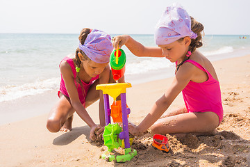 Image showing Two children playing with toys in the sand on the sea beach