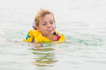 Image showing Five-year girl stuck out her tongue with pleasure swimming in the sea