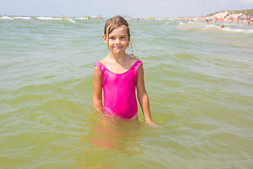 Image showing The girl in the pink bathing suit standing in the water of the sea