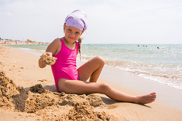 Image showing Girl digs a hole in the sand on the seashore