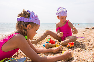 Image showing Two children playing in the sand on the beach resort